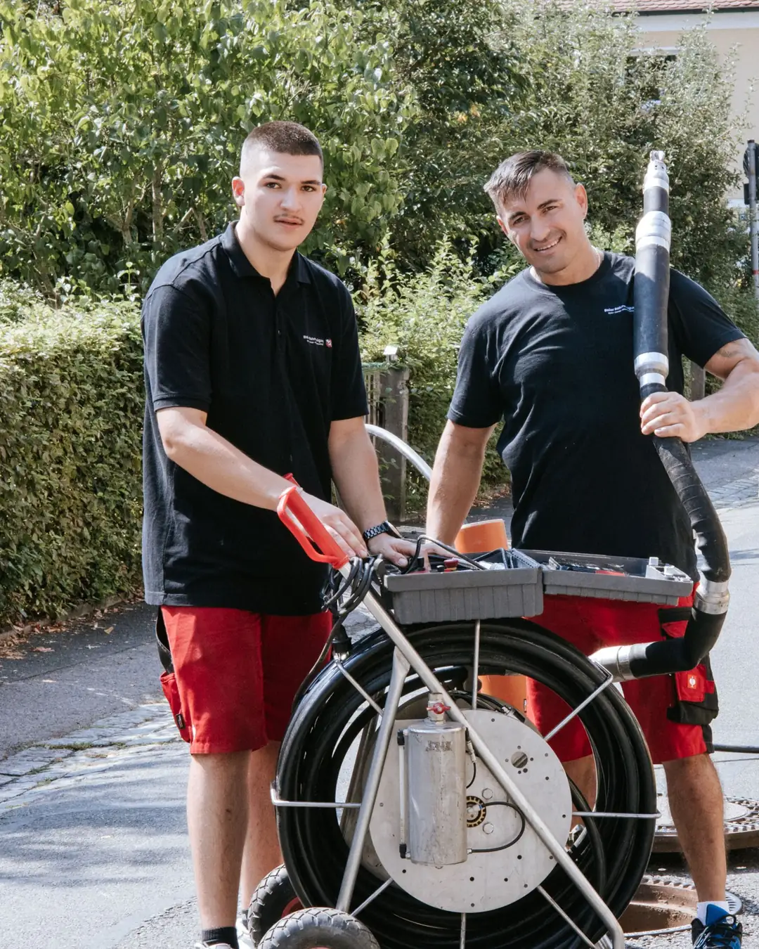 Zwei Techniker der Baier Rohrreinigung GmbH mit Fräsroboter vor dem Servicewagen